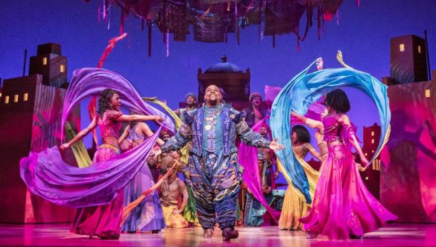 Genie (Trevor Dion Nicholas) in market surrounded by scarfs - photo by Johan Persson © Disney.jpg